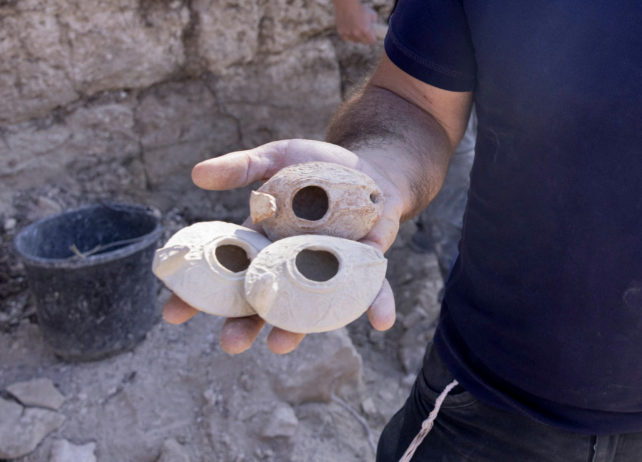 Close up image of person holding three clay lamps.