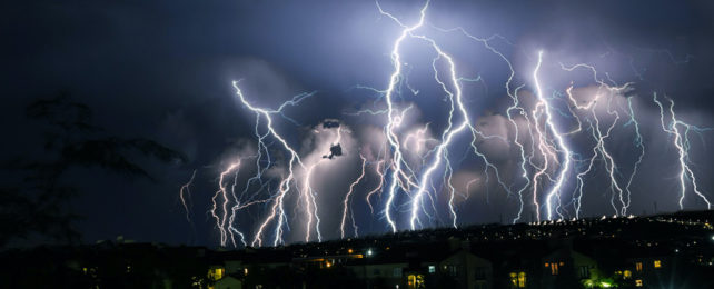 Multiple lightning strikes over a nighttime cityscape.
