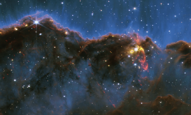 close up image of the cosmic cliffs with a bright spot indicating a star cluster