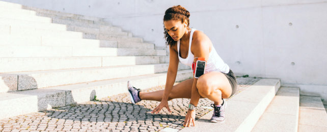 A woman stretches on some stairs during a workout.