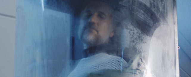 man in a translucent chamber with his eyes closed