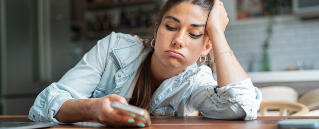 bored woman looking at her cell phone