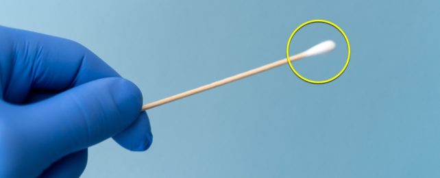 Blue Glove Holds Nasal Swab With Yellow Circle