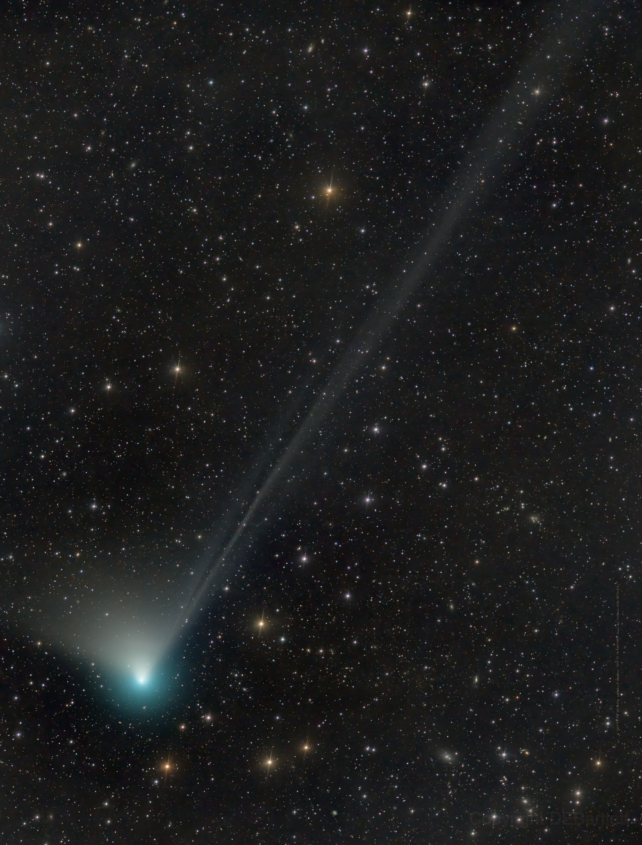 Blue-green comet with tail streaming behind it