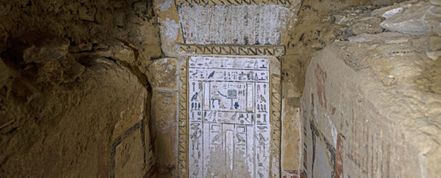 A narrow corridor leading to a door covered in hieroglyphs at the Saqqara dig site.