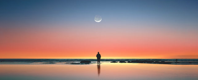 Human silhouette on beach at sunset under a crescent moon