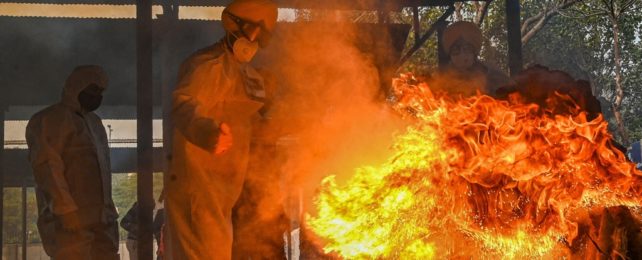 Men In Protective Suits Stand Around Fire