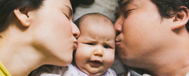 Two Parents Kiss Their Baby