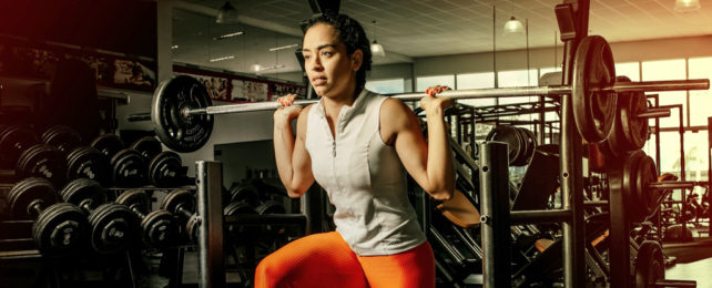 A woman in a gym lifts weights.