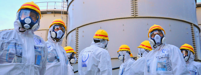 workers in masks and helmets in front of water storage tanks