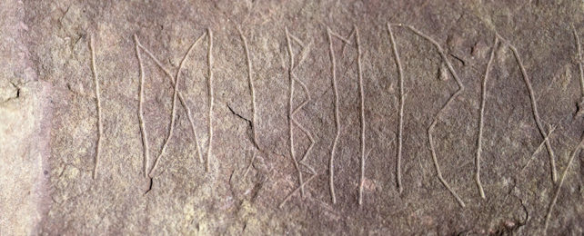 close up of a series of runes scratched into a stone face