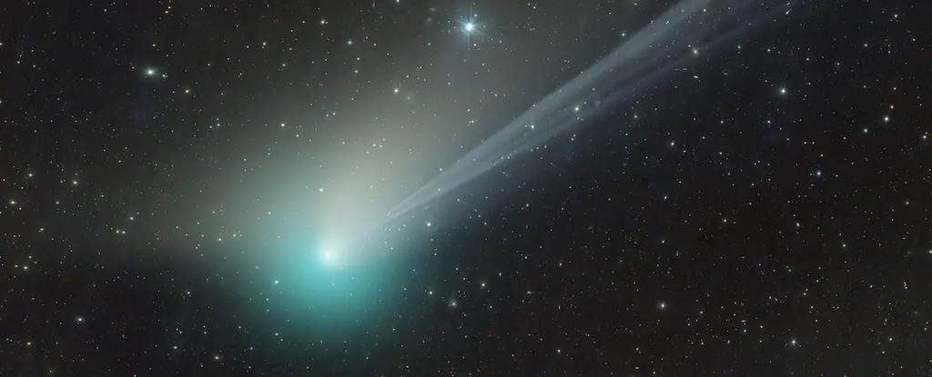Green comet with big tail trailing through starry sky
