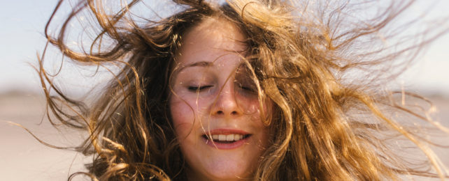 A woman's hair blows around her head and face.