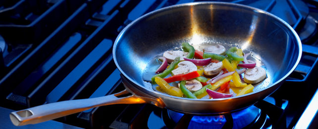 frying pan with vegetables on a blue-lit background