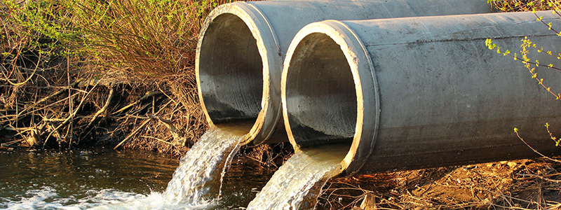 two concrete pipes emptying water into a stream