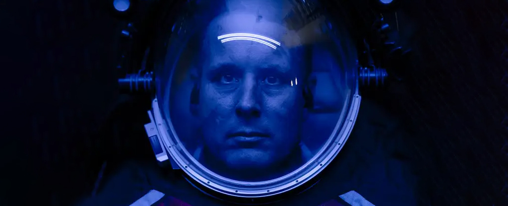 Close up of engineer's face in black space suit with blue lighting