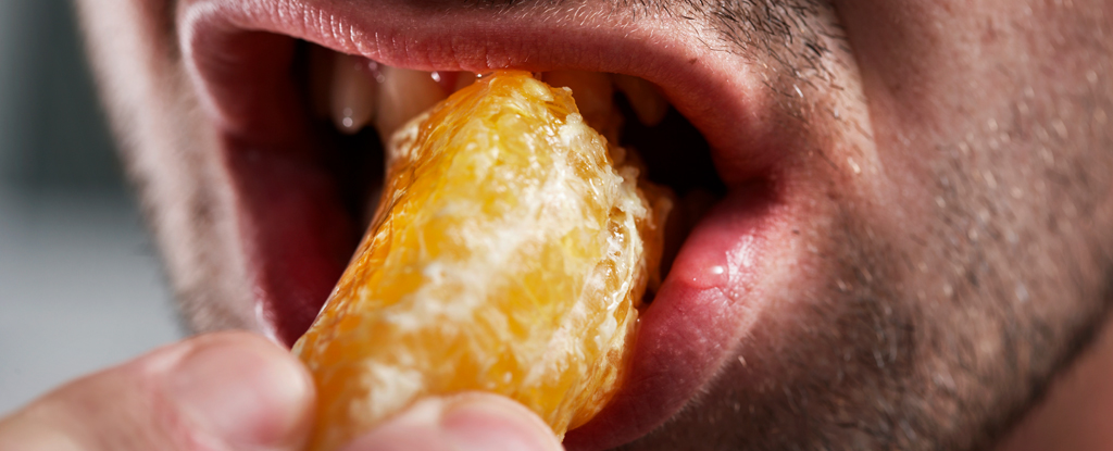 Close up of man taking a bite of mandarin