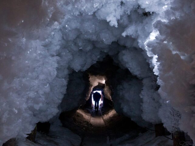 Buz kristalleri tünelinde yürüyen adam.