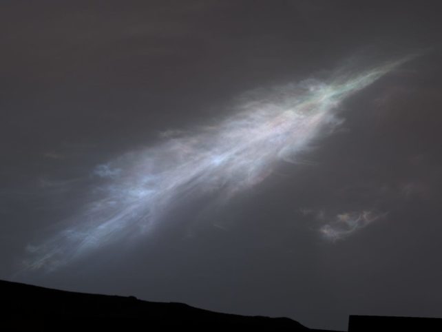 Wispy cloud over dark slope with hints of colors.