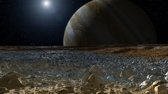 Terrain glacé et rocheux devant une vue de Jupiter et du Soleil.