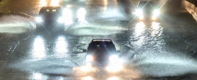 Cars Drive Through Flooded Road