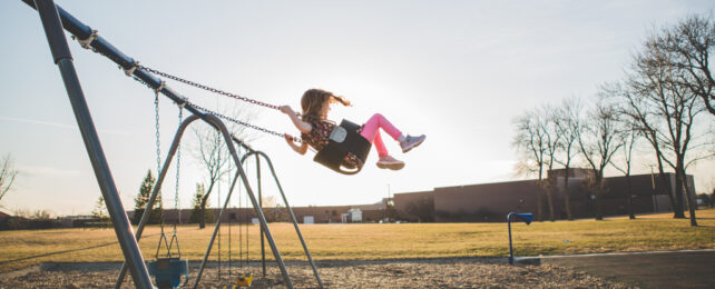 A little girl on a playground swing.