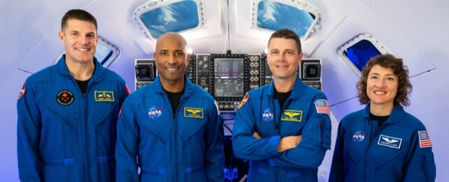 The Artemis II crew dressed in blue flight suits, in an Orion simulator at NASA’s Johnson Space Center in Houston.