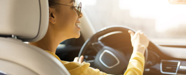 black woman with glasses holding a steering wheel