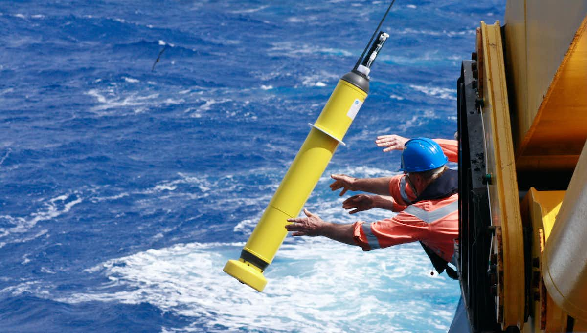 People throwing robotic floats from ship into ocean.