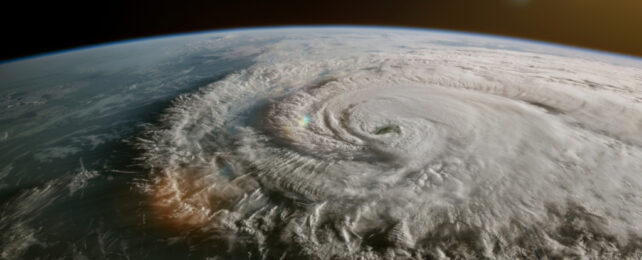 Huge tropical storm of swirling white clouds photographed from satellite over Earth.