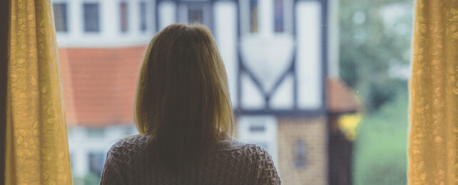 A woman looks out of her window.