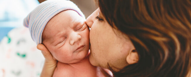 mother kissing newborn child