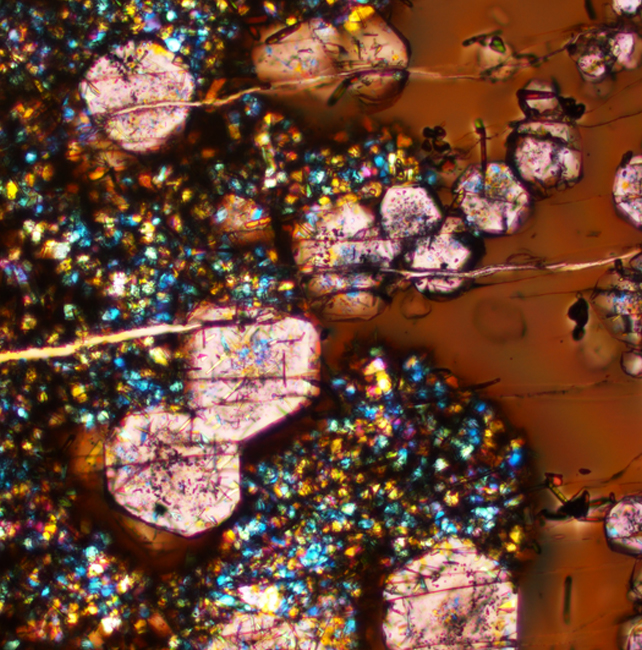 pinkish crystals among other shapes and colours on a brown background