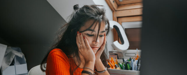 An anxious woman cradles her face in her hands.