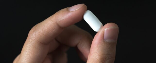 White Pill Held By Fingers