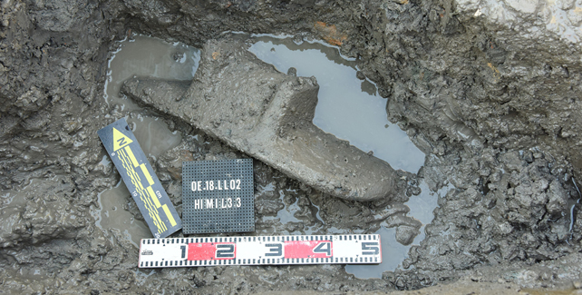 An ancient grinding stone in a muddy puddle.