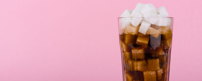 A glass of cola filled with sugar cubes.