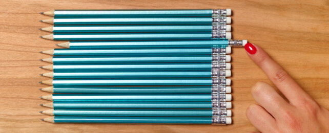 A hand straightening a row of pencils.