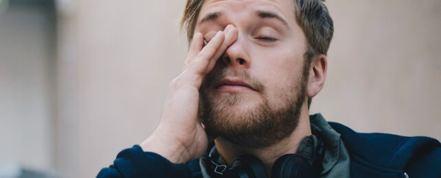 man rubbing his eyes