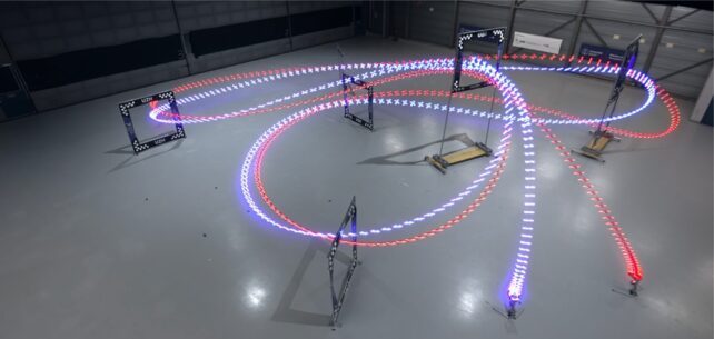 Time-lapse image of an autonomous drone (blue lights) and human-piloted drone (red lights) flying around race track with seven square gates.