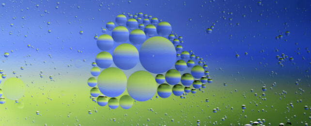 Cluster of oil drops in water on a blue-green background.