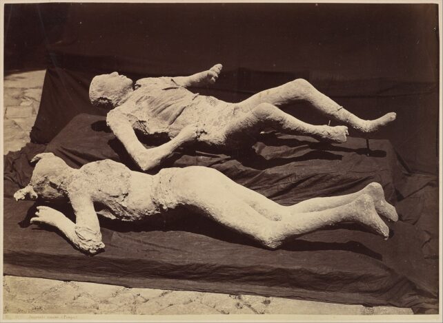 Plaster casts of two human victims, one lying face down the other on their back.