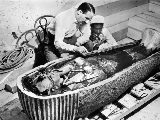 Old photograph of Carter standing over tut's mummy
