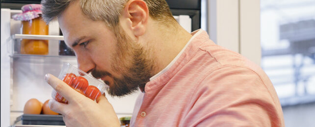 man sniffing tomato punnet