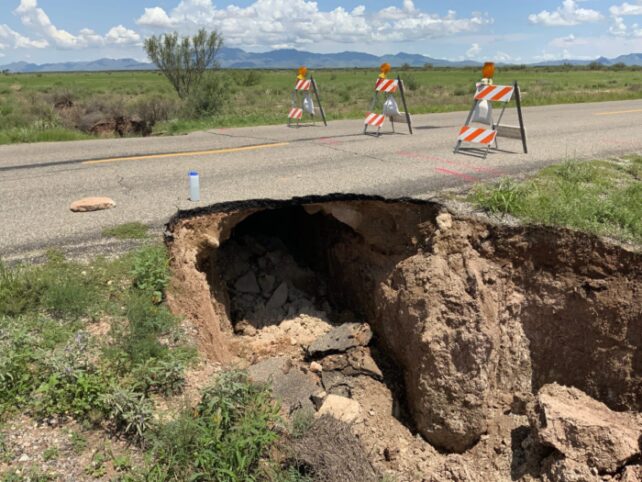 Fissure opened up beneath the road crossing a plain.