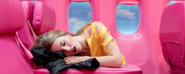 Woman pretending to sleep on a pretend inflatable pink plane
