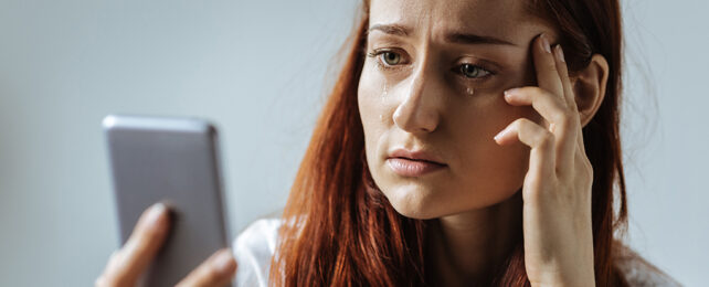 girl looking at her phone with tears on her face