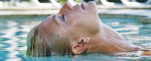 blonde woman laying back in a swimming pool