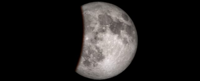 A close up of the Moon's surface with a small section darkened by Earth's shadow