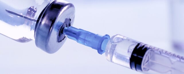 A syringe being injected into a vial